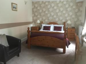 a bedroom with a bed and two night stands and a chair at Grove House Guest House in Telford