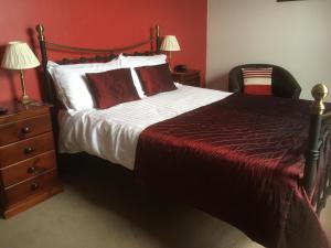 a bedroom with a large bed with red walls and a chair at Grove House Guest House in Telford