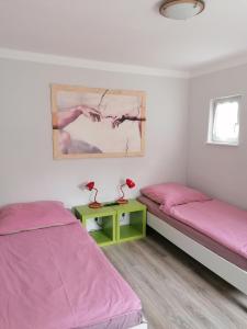 - 2 lits dans une chambre avec des draps roses et une table dans l'établissement Apartment North City Hannover, à Hanovre