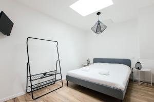 a white bedroom with a bed and a mirror at Appartement spacieux et lumineux avec climatisation et belle hauteur sous plafond - Halle 2EME in Castillon-la-Bataille