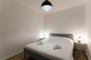 een slaapkamer met een wit bed met 2 kussens erop bij Appartement spacieux et lumineux avec climatisation Halle 1ER in Castillon-la-Bataille