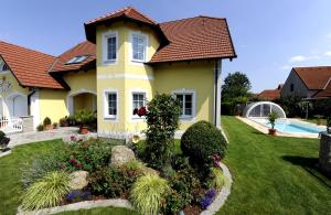 une maison jaune avec une piscine dans la cour dans l'établissement Gästehaus Familie Trachsler, à Rohrendorf bei Krems