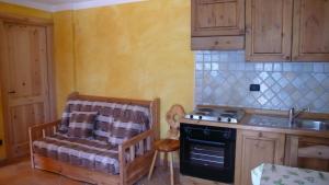 a kitchen with a stove and a chair in it at Residence Les Myosotis in Champoluc