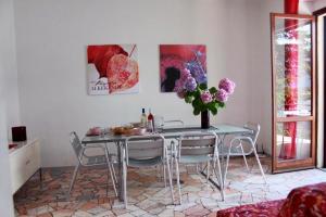 stół jadalny z krzesłami i wazon kwiatów w obiekcie Casa Spiaggia w mieście Brezzo
