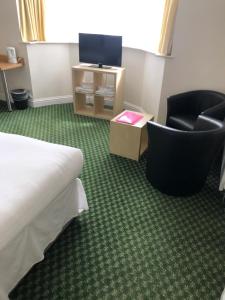 
a room with a bed, chair and a television at Granby Hotel in Gravesend
