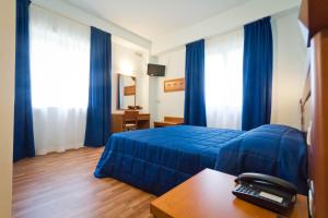 een hotelkamer met een blauw bed en blauwe gordijnen bij Hotel Donnini in Assisi