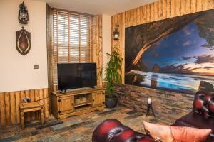 a living room with a television and a painting on the wall at Deluxe Pirate's Cove Themed Apartment in St Austell