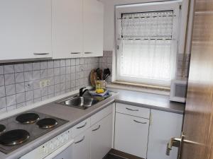 eine Küche mit weißen Schränken, einem Waschbecken und einem Fenster in der Unterkunft FÜRTH Wohnung mit WLAN und Parkplatz in Fürth