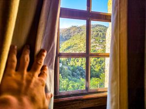 a person is looking out of a window at a mountain at Casa Carolina in Vila Seca