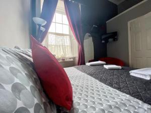 a bed with a red blanket and pillows on top of it at 16 Pilrig Guest House in Edinburgh