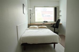 a bedroom with a bed and a desk and a window at Matkustajakoti Evakko in Seinäjoki