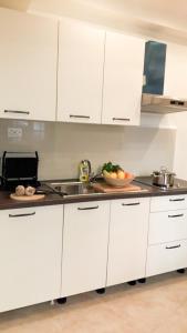 a kitchen with white cabinets and a sink at Apartament Colosseum view in Pula