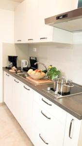 a kitchen with white cabinets and a bowl of vegetables on a counter at Apartament Colosseum view in Pula