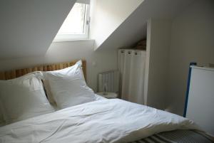 a bedroom with a bed with white sheets and a window at La Cour Soubespin in Lille