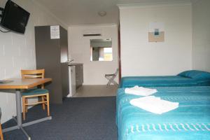 Habitación de hotel con cama, escritorio, mesa y escritorio. en Cedar Lodge Motel en Townsville