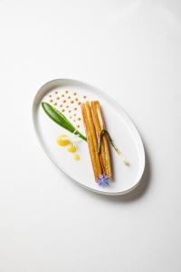 a plate of carrots and beans on a white plate at Relais et Châteaux Le Chambard in Kaysersberg