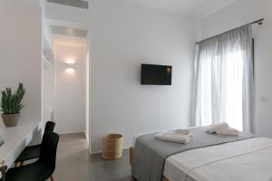 a white bedroom with a bed and a window at Vorta Naxos in Naxos Chora