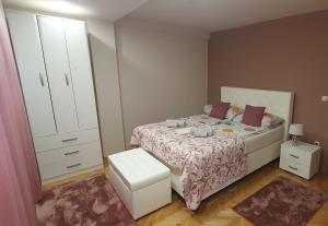 a bedroom with a bed with a dresser and a mirror at Apartman Lux K in Bijeljina