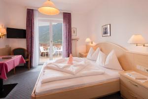 a hotel room with a bed and a balcony at Hotel Bellevue in Tirolo