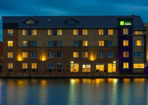 a building with a sign on it next to the water at Holiday Inn Express Cardiff Bay by IHG in Cardiff