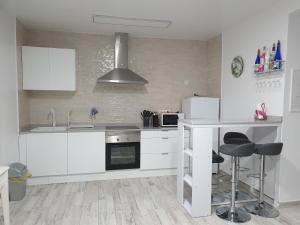a kitchen with white cabinets and a counter with stools at Apto con Hidromasaje sweet Charco by flamingo house in Arrecife