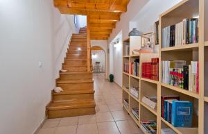 a hallway with wooden stairs and bookshelves at Odyssey House in Chania