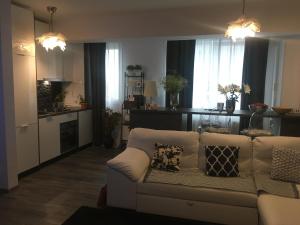 sala de estar con sofá blanco y cocina en True Modern - apartment, en Valea Lupului