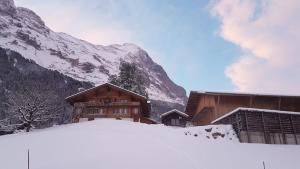 a snow covered building with a mountain in the background at Chalet bei der Arve in Grindelwald