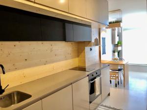 eine Küche mit weißen Schränken und einer Spüle in der Unterkunft Apartamento T1 no centro TÊ-U in Torres Vedras