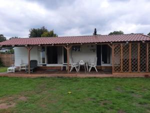 a house with a deck and chairs on it at chalet Lobke in Voorthuizen