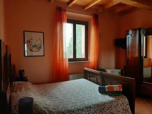 a bedroom with a bed and a window with orange curtains at Agriturismo Il Sole in Rivarolo del Re ed Uniti