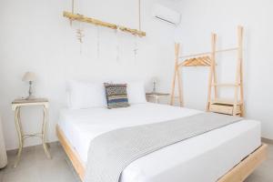 białe łóżko w pokoju z 2 drewnianymi panelami w obiekcie Bella vista Suites w mieście Karpatos