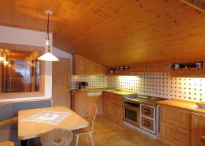 eine Küche mit Holzschränken und einem Holztisch mit einem Esszimmer in der Unterkunft Apartments Hubertushof in Toblach