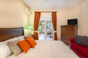 ein Schlafzimmer mit einem Bett und einem roten Sofa in der Unterkunft Villa Maya in Pallíni