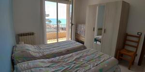 1 dormitorio con 2 camas y balcón con vistas al océano en Appartamento Giardino, en Ventimiglia
