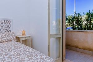 a bedroom with a bed and a balcony with a window at Sunrise over the sea in Noto Marina