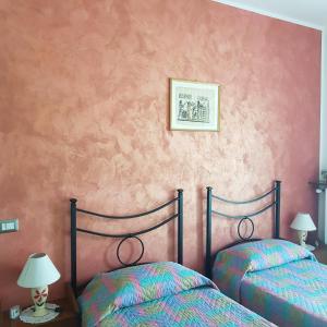 two beds in a bedroom with pink walls at B&B I Lazzarini in Sarnico