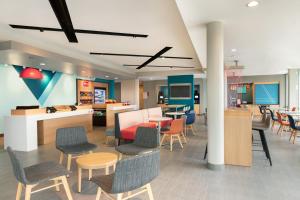 a lobby with chairs and tables and a cafeteria at Avid Hotel Cedar Rapids South - Arpt Area, an IHG Hotel in Cedar Rapids