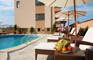 a pool with chairs and a table with a bowl of fruit at Stanny Court ApartHotel in Nesebar