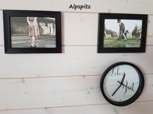 3 Bilder und eine Uhr an der Wand in der Unterkunft Apartment Kramer und Alpspitz in Garmisch-Partenkirchen