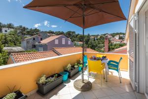a balcony with a table and an umbrella at Apartments Priko 63 in Mali Lošinj