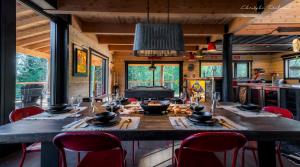 a dining room with a long table with red chairs at Le Kanawata - Les Chalets Spa Canada in La Malbaie