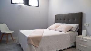 1 dormitorio con 1 cama con sábanas blancas y silla en Apartamento los Acantilados Nº 2 Cobreces, en Cóbreces