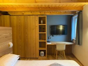 a bedroom with a desk with a tv on a wall at Hotel Centrale in Peio