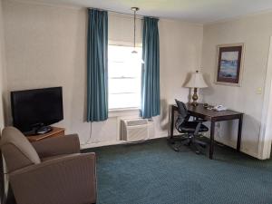 um quarto de hotel com uma secretária, uma cadeira e uma janela em Azalea Inn & Suites em Wilmington