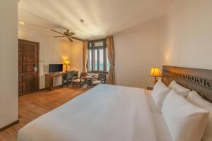 a bedroom with a large white bed and a living room at Chu Hotel in Danang