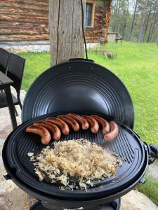 a group of sausages and onions cooking on a grill at Kuukkeli Log Houses Porakka Inn in Saariselka