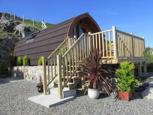 a small house with a wooden staircase in front of it at Loch Cromore Holiday Pods in Cromore