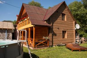 a log cabin with a porch and a pool at Шале " Компанійське" in Slavske