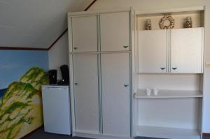 een kamer met een witte kast en een koelkast bij De strandkamer in Oostkapelle